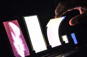 写真17　コニカミノルタの0.35 mmの薄さで折り曲げが出来る樹脂基板のフレキシブル有機ELパネル左から，パターニングアートパネル，白色フレキシブルパネル，カラー調色フレキシブルパネル。（撮影：Granage LLP）